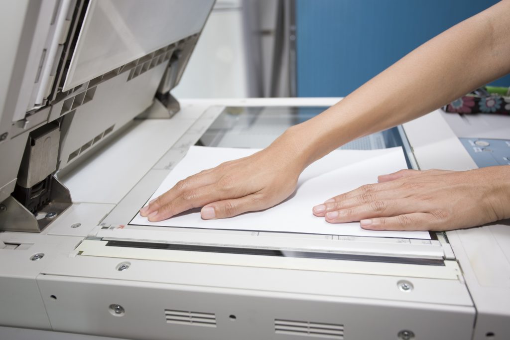 hands putting a sheet of paper into a copying device